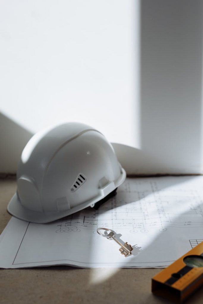 pexels photo 8470864 Close-up of a safety helmet and key on a blueprint, symbolizing construction and planning.